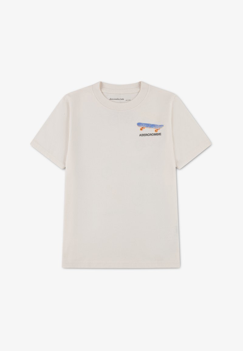 Παιδικό T-shirt μπεζ με κοντά μανίκια, με μια μικρή μπλε και πορτοκαλί σκέιτμπορντ και την επιγραφή "ABERCROMBIE" στο πάνω αριστερό μέρος του στήθους.