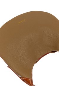 Prodotto in pelle marrone con finitura testurizzata, dotato di un logo dorato e cuciture in contrasto color nocciola lungo i bordi. Forma semicircolare.