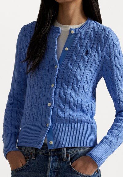 Cardigan en maille torsadée bleu clair avec des manches longues, présentant un ourlet et des poignets côtelés, une fermeture à boutons et un petit logo sur la poitrine gauche.