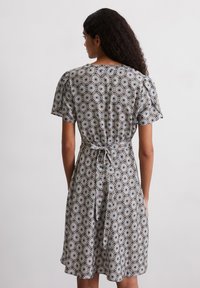 Blumengemustertes Kleid in Schwarz und Weiß, kurze Ärmel, tailliert mit Kordelzug, knielang, mit lockerem Sitz und leichter Textur.