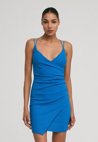 Vestito bodycon blu con spalline sottili, scollatura a V profonda e design a portafoglio. Il tessuto è liscio con una sottile trama a coste.