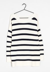 Pull blanc en tricot avec des rayures horizontales noires suspendu à un cintre noir sur un fond blanc.