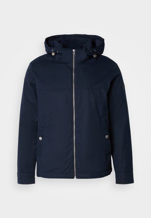 Giacca impermeabile blu navy con chiusura a zip frontale, cappuccio regolabile con cordoncino, due tasche laterali e dettagli in hardware argentato. Tessuto di consistenza liscia.