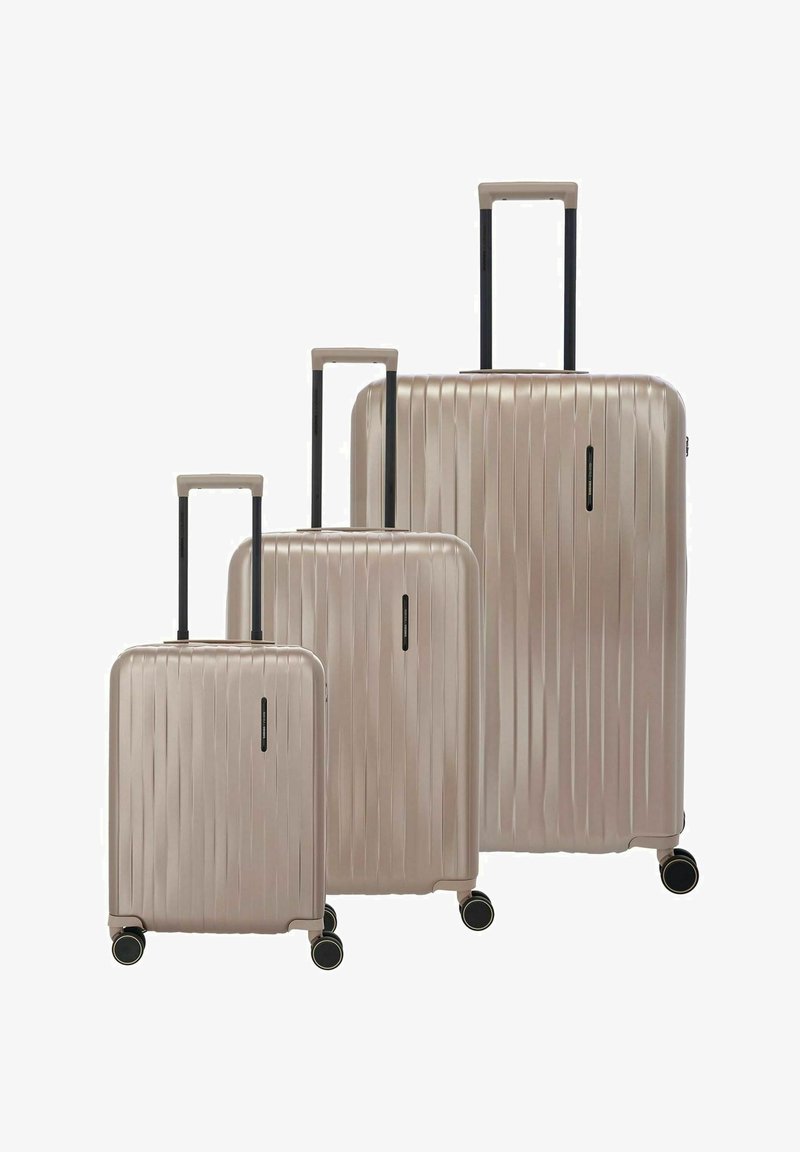 Tres maletas rígidas color beige de tamaños pequeño, mediano y grande, con asas telescópicas extendidas y cuatro ruedas negras cada una.