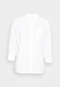 Chemise blanche à manches longues avec boutons et une poche sur la poitrine gauche, avec des poignets pliés, présentée sur un fond gris clair.