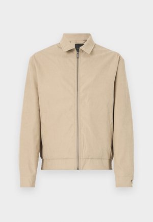 Bēša viegla jaka ar divrindu rāvējslēdzēju, apkakli, sānu kabatām un elastīgām piedurknēm. Gluda tekstūra un eleganta forma bez redzamām rakstīm.