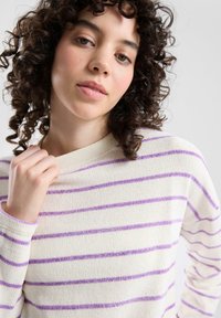 Biały sweter z fioletowymi poziomymi paskami, wykonany z fakturowanego materiału. Posiada okrągły dekolt i długie rękawy.