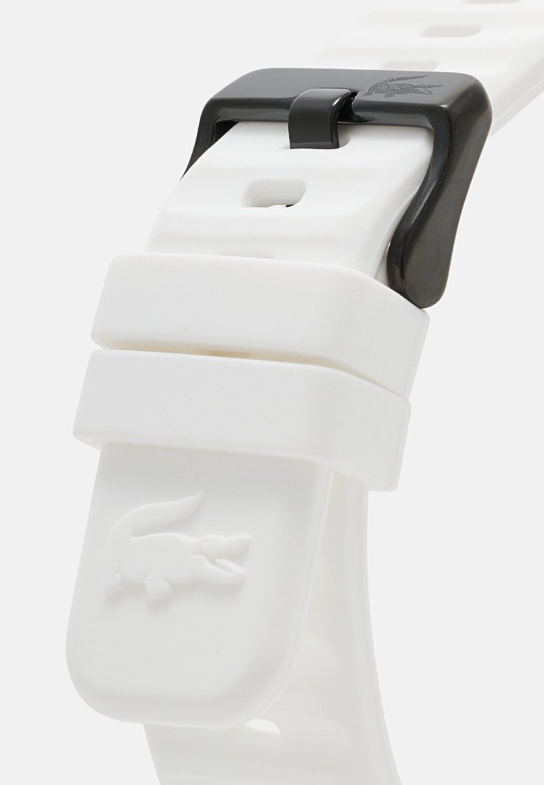 Bracelet de montre en caoutchouc blanc avec une surface texturée, boucle réglable et fermoir noir. Présente un petit logo en relief sur un côté.