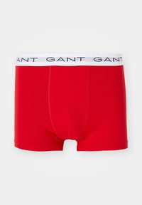 Boxers rouges pour hommes avec ceinture élastique blanche arborant la marque « GANT » en bleu marine, présentés sur fond blanc.