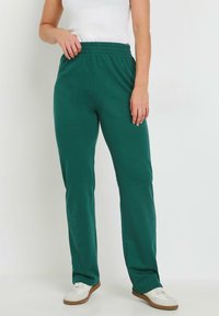 Groene katoenen broek van een mengsel met een elastische tailleband, rechte pijpen en een soepele textuur, gecombineerd met witte schoenen.