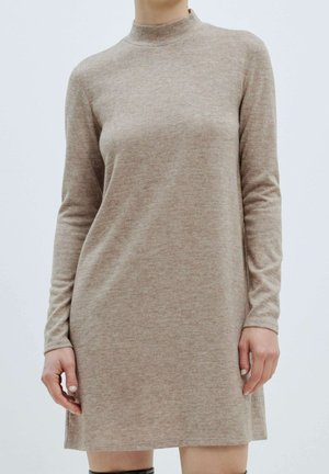 Robe à manches longues et col haut en tricot beige clair. Présente une coupe décontractée et des fentes latérales pour plus de liberté de mouvement. Texture lisse, design minimal.