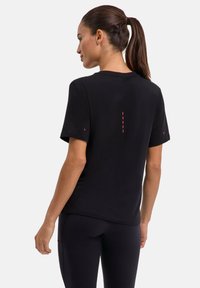 Zwart T-shirt met korte mouwen en een ronde halslijn met rode accenten op de achterkant. Gemaakt van zachte stof, aansluitend design.