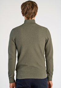 Grüner Strickpullover mit hohem Kragen, gerippten Bündchen und Saum, der einen strukturierten Stoff und eine figurbetonte Silhouette bietet.