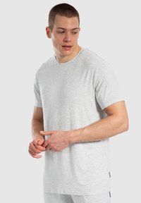 Grijze T-shirt met korte mouwen van een lichtgewicht, zachte stof, met een ronde halslijn en een losse pasvorm. Voorzien van een subtiele merklabel aan de zijkant.