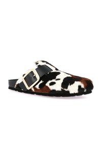 Zoccoli slip-on pelosi con stampa a mucca bianca e nera, dettagli marroni e cinturino nero con fibbia dorata. Texture morbida e forma arrotondata.