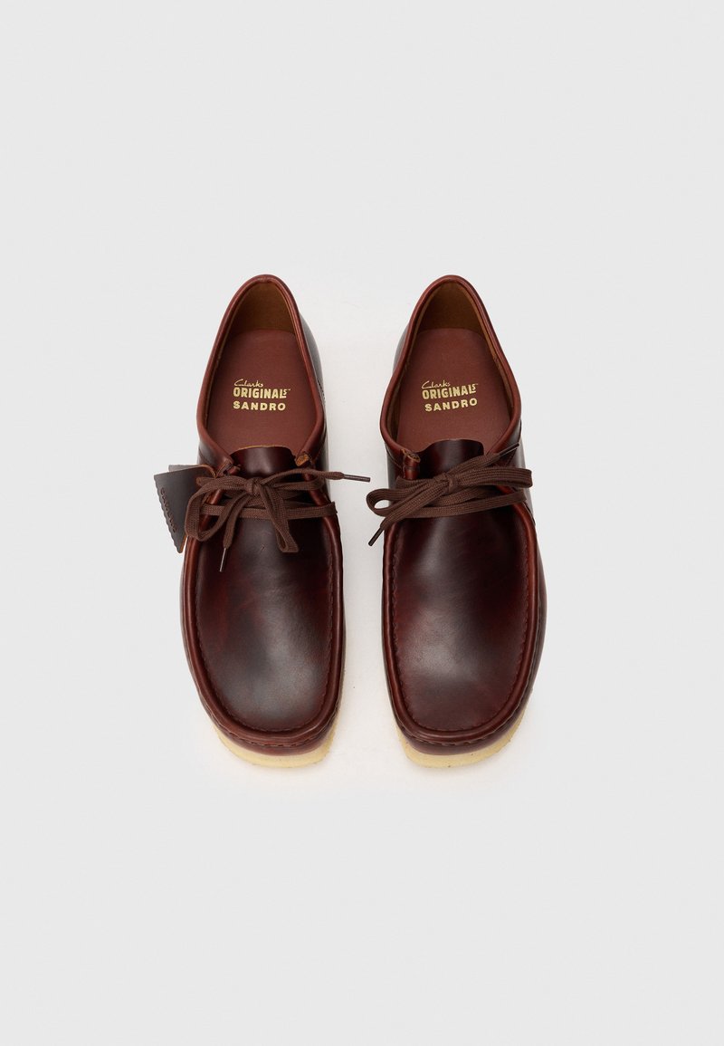 Chaussures en cuir marron avec un bout arrondi, un laçage et une semelle en caoutchouc beige. Présentent une couture et une semelle intérieure marquée.