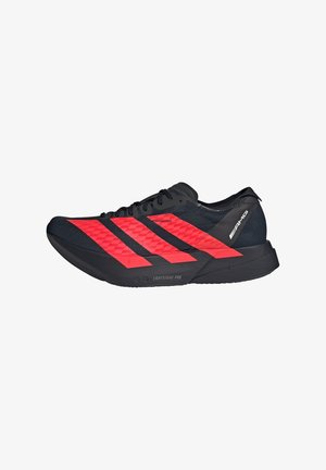 Chaussure de sport noire avec des accents rouge vif, dotée d'une tige en mesh légère, d'un design à trois bandes et d'une semelle sculptée pour une meilleure adhérence.