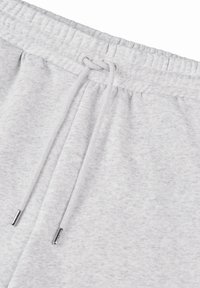 Pantalons de jogging en polaire gris avec une taille élastique, cordon de serrage ajustable et texture lisse. Comprend des embouts métalliques sur le cordon.