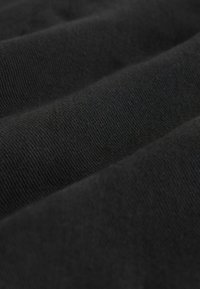 Black cotton fabric with a textured surface, featuring subtle ribbed patterns and slight undulations for a soft, flexible appearance.