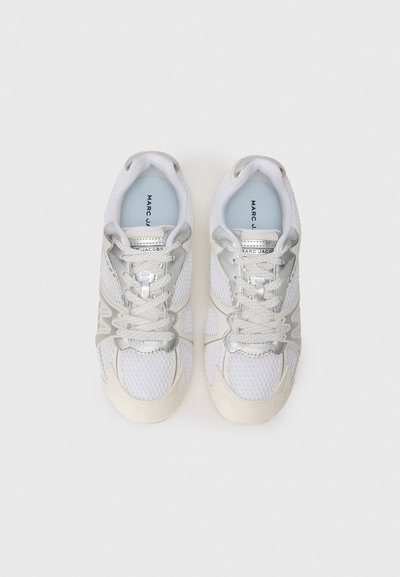 Fehér hálós sportcipők ezüst díszítéssel, textúrált gumitalppal és kerek orral. Tartalmazza a fűzőt és a márkázást a talpbetéten.