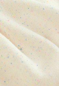 Tissu tricoté de couleur blanc cassé avec des éclats multicolores en rose, bleu et jaune. Texture douce, motif de trame visible sur l'ensemble.