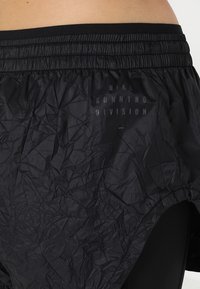 Svarta löparshorts med krinklad textur, elastiskt midjeband och subtilt tryckt Nike Running Division-logga. Lätt och ventilerande tyg.