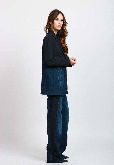 Blazer in denim con parte superiore blu scuro e parte inferiore in denim più chiaro, abbinato a pantaloni coordinati con strisce laterali e vestibilità morbida.