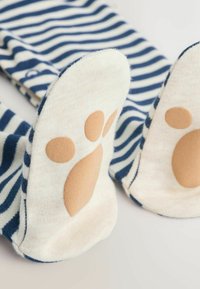 Calzini a righe con motivo blu navy e bianco, caratterizzati da accenti di impronte di zampe color crema su un tallone beige. Tessuto morbido con texture a coste.