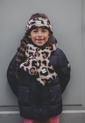 Zwarte gewatteerde jas, sjaal van luipaardprint en haarband. De sjaal valt om de nek, de haarband ligt op het haar, beide hebben een zachte textuur.