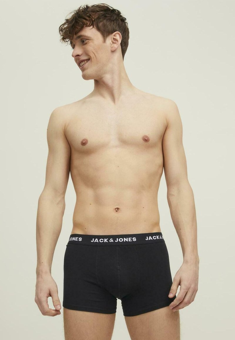 Black cotton boxer briefs with a white "JACK & JONES" logo on the elastic waistband, worn by a model with short curly hair.