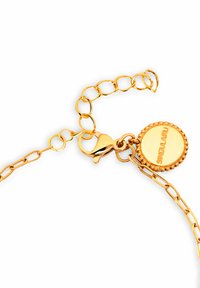 Pulsera de metal dorado con diseño de cadena, cierre de langosta y un charm circular con borde de cuentas y texto grabado.