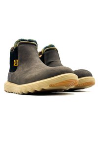 Bottes chelsea en suède gris avec une semelle en caoutchouc texturé, doublées de tissu à carreaux et dotées de panneaux élastiques sur les côtés pour un enfilage facile.