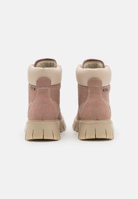 Rosa semskede ankelstøvler med beige lærkrave, mønstrede søm og tyk, teksturert gummisåle. Bakfra som viser støvlens konstruksjon.