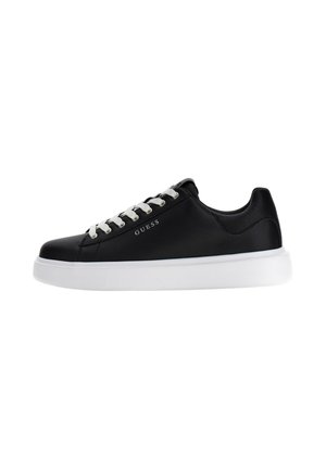 Sneaker basse nere Guess con lacci bianchi e suola bianca spessa, logo laterale visibile, materiali lisci e strutturati sulla tomaia.