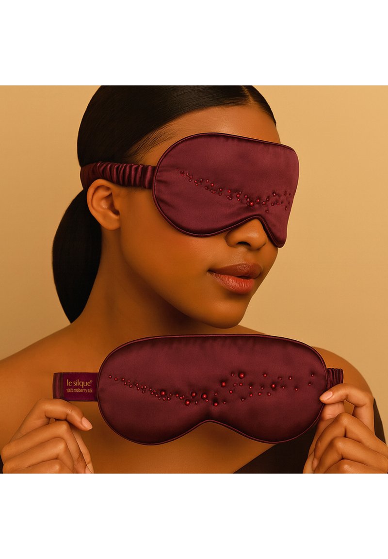 Maschera per dormire color bordeaux in seta, caratterizzata da una texture liscia con decorazioni di perline e una fascia elastica per una vestibilità sicura.