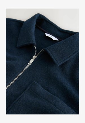 Tume sinine villasegu jakk, millel on krae, eest lukuga ja üks tasku. Tekstureeritud kangas ja hõbedased lukukandid.