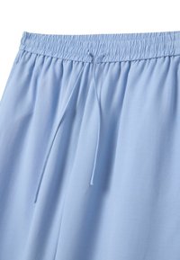 Helle blaue Shorts aus weichem Stoff, mit einem elastischen Bund und Kordelzug, sowie einer glatten Textur ohne Muster.
