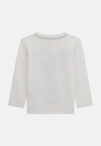 Langarmshirt in Hellgrau, aus weicher Baumwolle gefertigt. Mit einem runden Ausschnitt, der einfache Nähte aufweist, und einem geraden Saum.