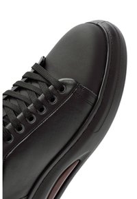 Sneaker in pelle nera con punta arrotondata, suola texturizzata, lacci rotondi e occhielli in argento. Presenta una finitura liscia e dettagli di cucitura sottili.