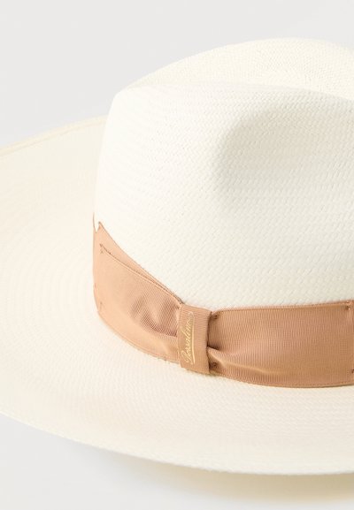 Λευκό ψάθινο καπέλο με φαρδύ γείσο και ανοιχτό καφέ κορδέλα δεμένη σε φιόγκο γύρω από τη βάση του στεφανιού.