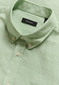 Camicia color verde chiaro con colletto, realizzata in tessuto testurizzato, con etichetta del marchio nera e bottoni chiari con centri verdi.