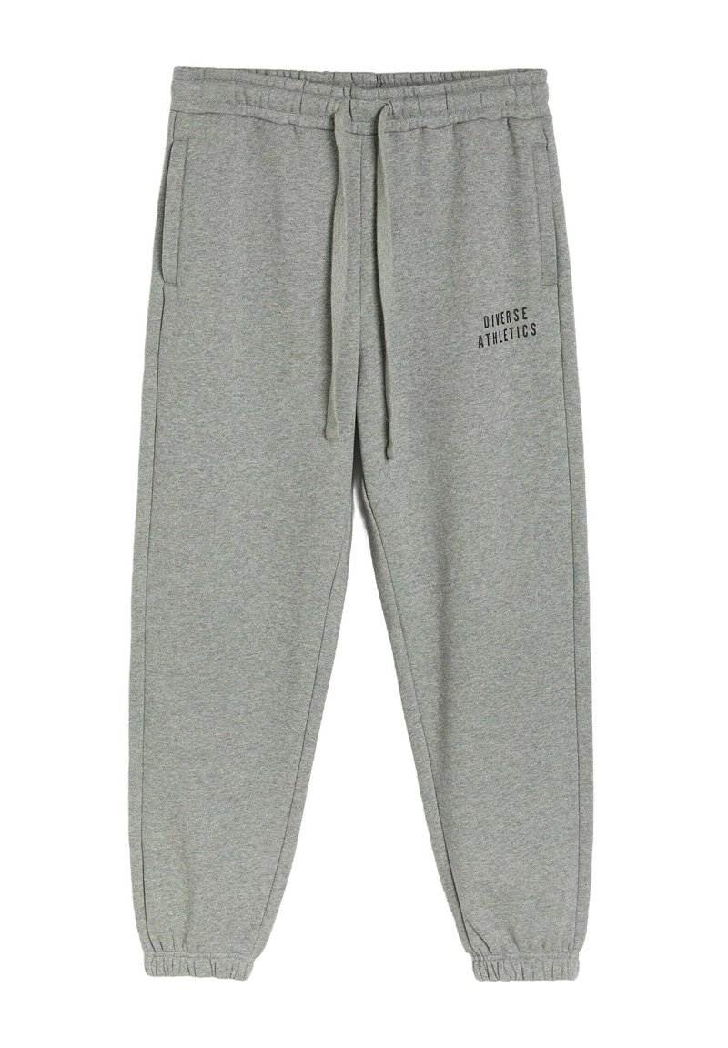 Szare dresy z elastycznym paskiem w talii, sznurkiem do regulacji i bocznymi kieszeniami. Na jednej nogawce nadrukowany jest napis „Diverse Athletics”. 