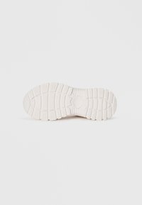 White sneaker sole with textured rubber, featuring deep grooves and a rounded toe. Reinforced heel and patterned treads for traction.