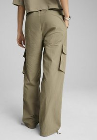 Kaki cargo hlače s sproščenim krojem, ki imajo stranske žepke, nabrane robove in lahkotno, teksturirano tkanino.