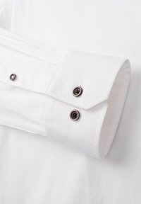 Weißer Hemdärmel mit glatter Textur, dunklen Metallknöpfen und kontrastierenden Nähten. Maßgeschneidertes Design mit ordentlichem Abschluss.