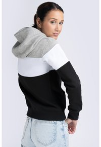 Hoodie med färgblockdesign: grå, vit och svart. Har en känguruficka, ribbade ärmslut och en mjuk tygkänsla.