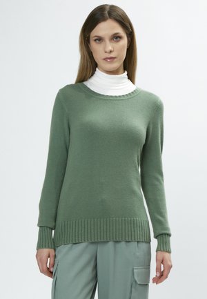 Groen gebreid shirt met lange mouwen, geribbelde manchetten en onderkant, ronde halslijn, gecombineerd met een witte coltrui eronder.