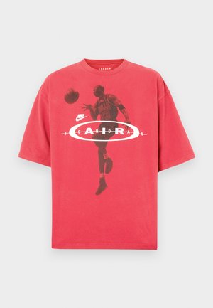 Piros pamut póló kerek nyakkivágással, laza szabással, kosárlabdázót ábrázoló grafikus nyomattal, rajta a "Jordan" felirat és a Nike logó.