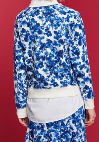 Blommönstrad sweatshirt i vitt och nyanser av blått, med ribbad nederkant och ärmslut, rund halsringning och raglanärmar.