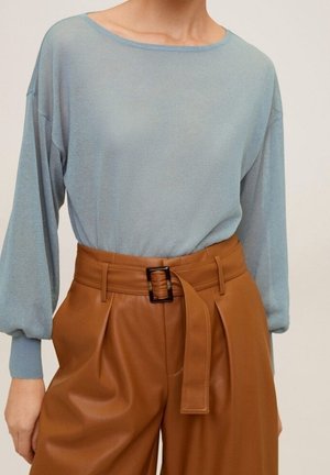 Personne portant un haut bleu clair à manches longues rentré dans un pantalon en cuir marron taille haute avec une ceinture large et une boucle rectangulaire.